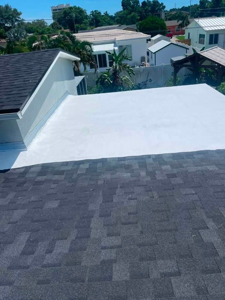 Close-up of a flat TPO roof membrane with an adjoining shingle roof visible