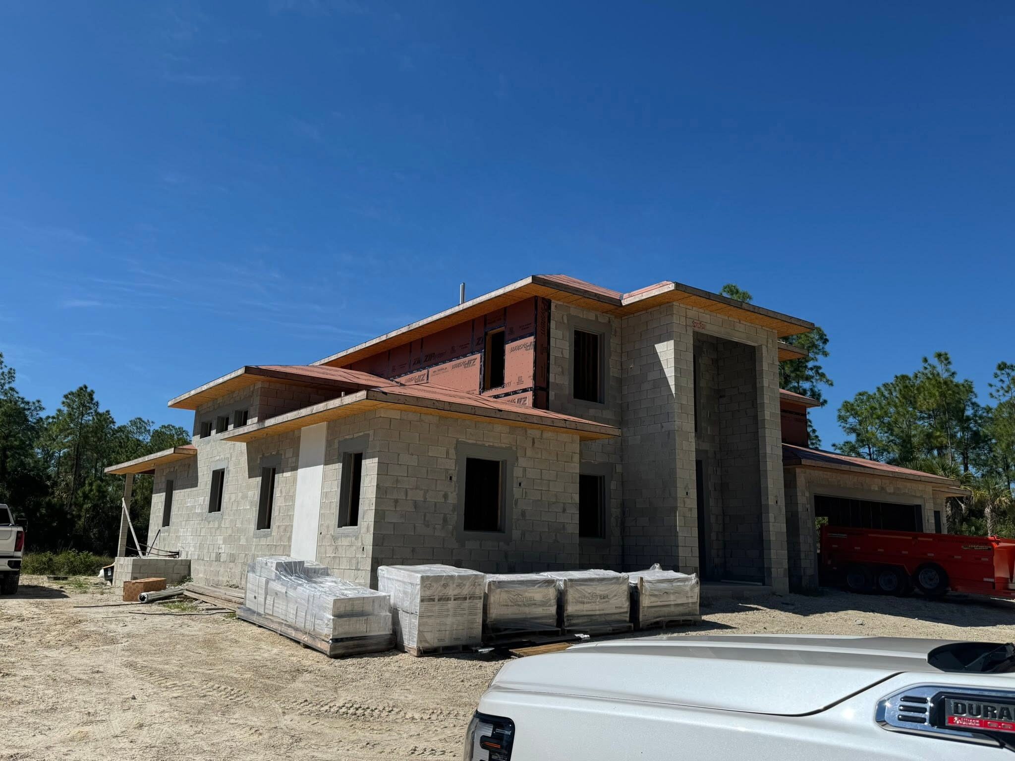 New construction home mid-build with CMU block walls and ZIP System sheathing roof overhangs