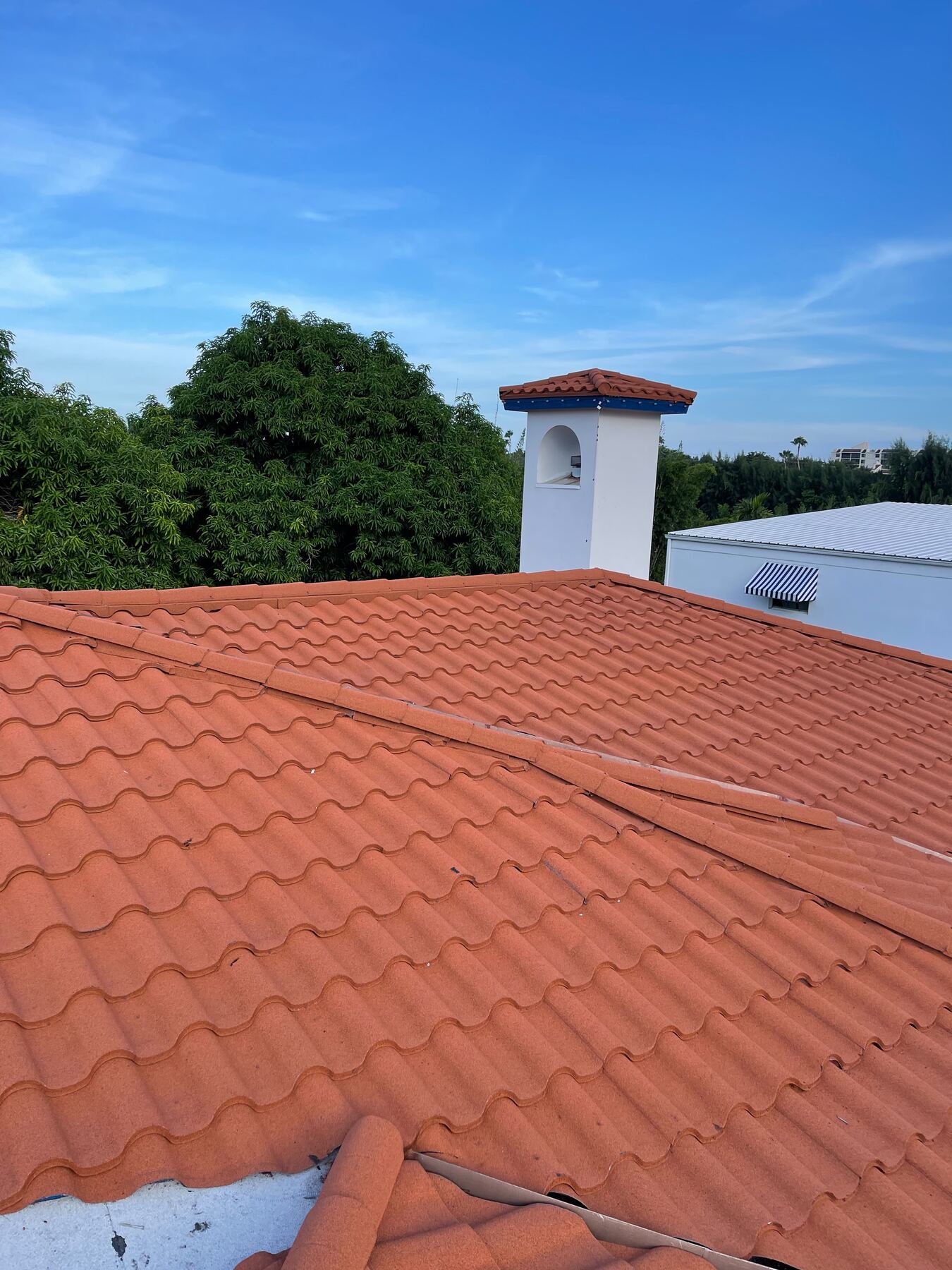 Barrel tile roof valley with a white turret and tile roof in the background