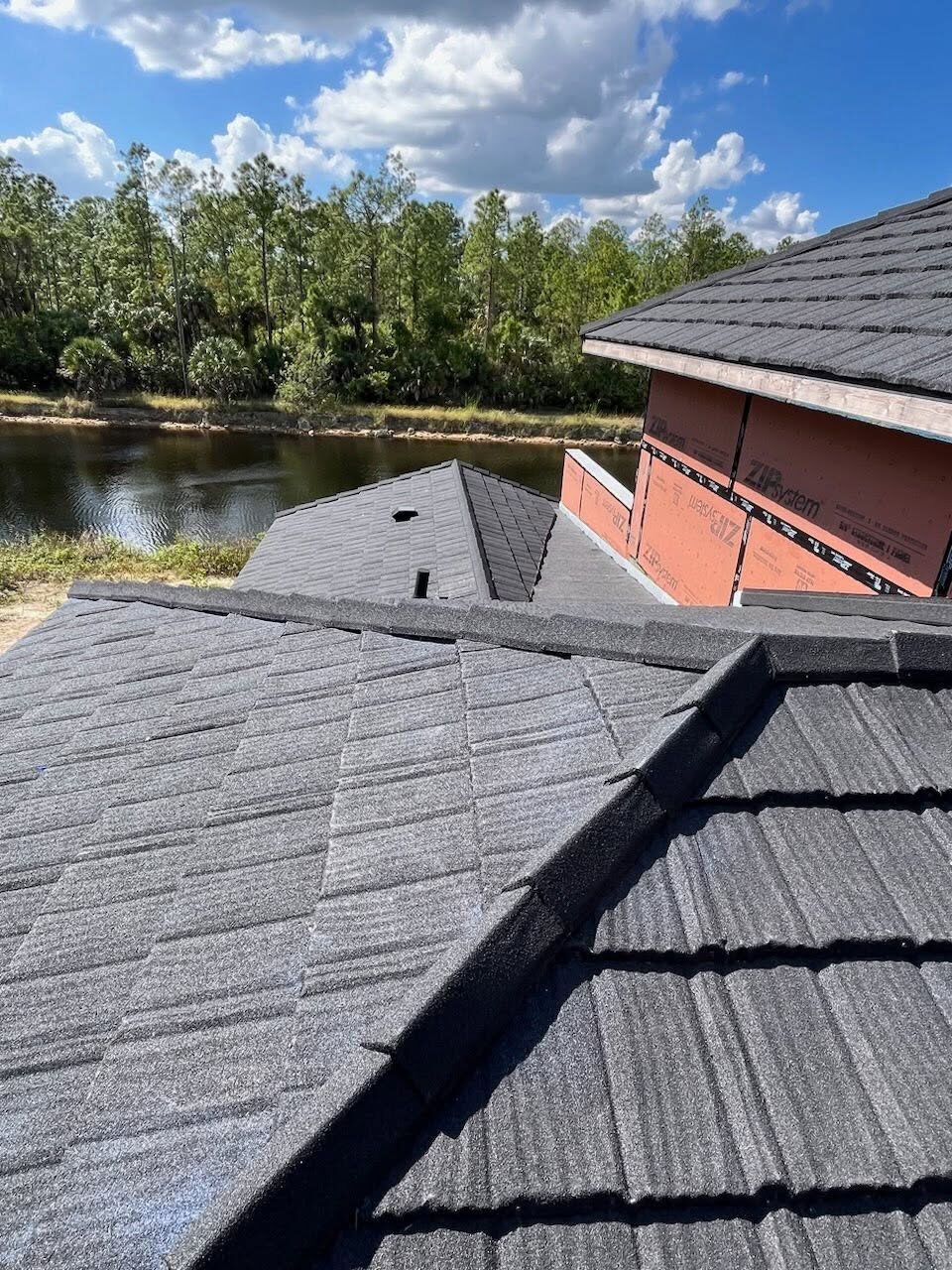 New construction roof dry-in with ZIP System sheathing near a pond