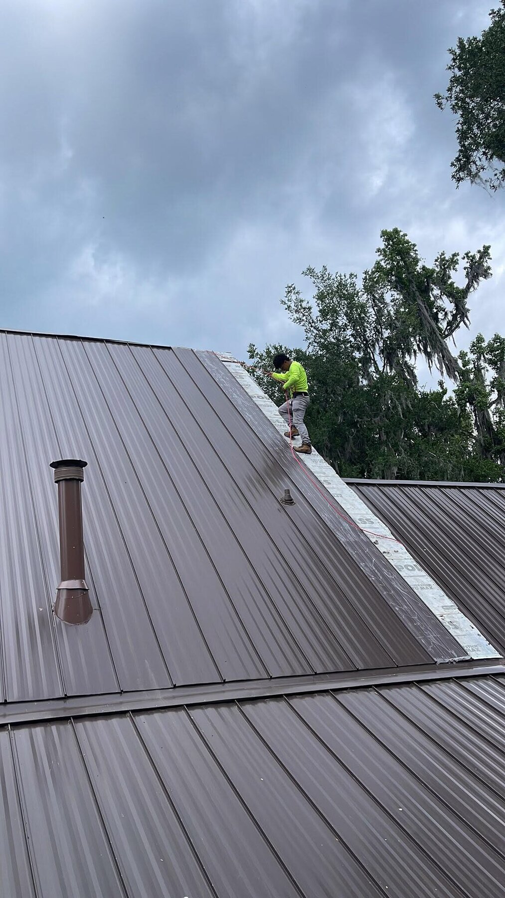 AR Legacy Roofing crew member installing a standing-seam metal roof
